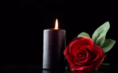 vorderansicht-der-dunklen-kerze-mit-roter-rose-auf-der-dunklen-oberflaeche_179666-37910