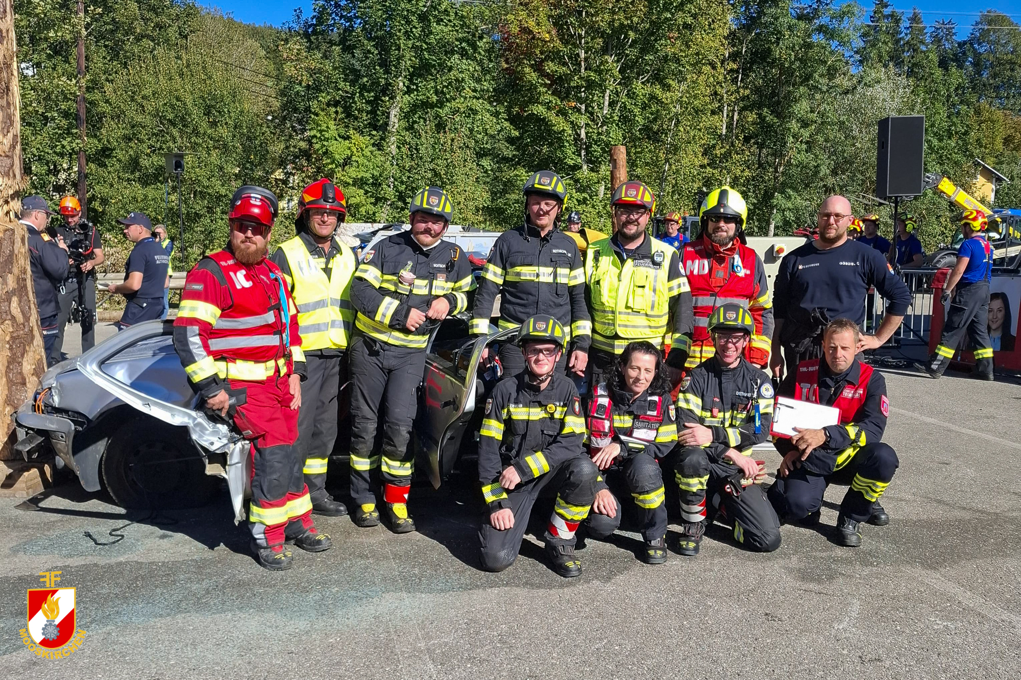 Feuerwehrleute posieren mit verunfalltem Auto bei Übung in Österreich